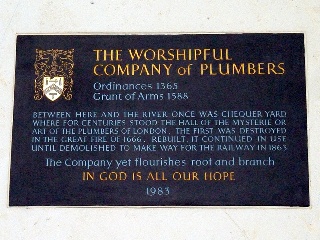 Slate plaque № 11684 - The Worshipful  Company of Plumbers    Ordinances 1365  Grant of Arms 1588    Between here and the river once was Chequer Yard  where for centuries stood the hall of the mysterie or  art of the plumbers of London. The first was destroyed  in the great fire of 1666. Rebuilt, it continued in use  until demolished to make way for the railway in 1863    The Company yet flourishes root and branch    In God is all our hope  1983