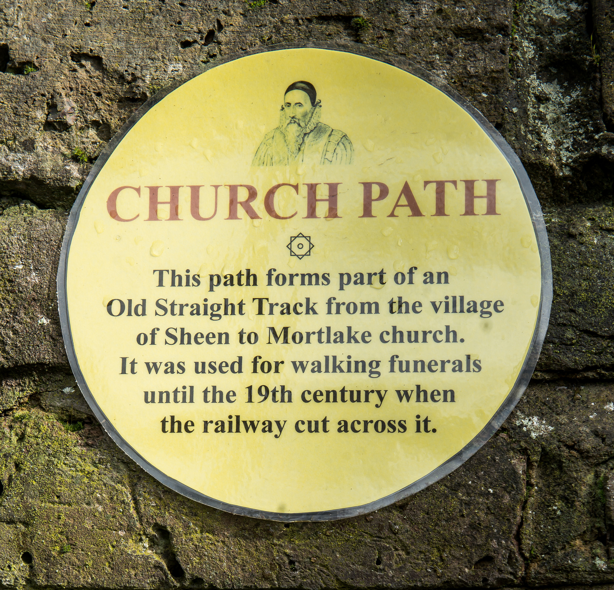 Church Path, Mortlake yellow plaque - Church Path  This path forms part of an Old Straight Track from the village of Sheen to Mortlake church.  It was used for walking funerals until the 19th century when the railway cut across it.