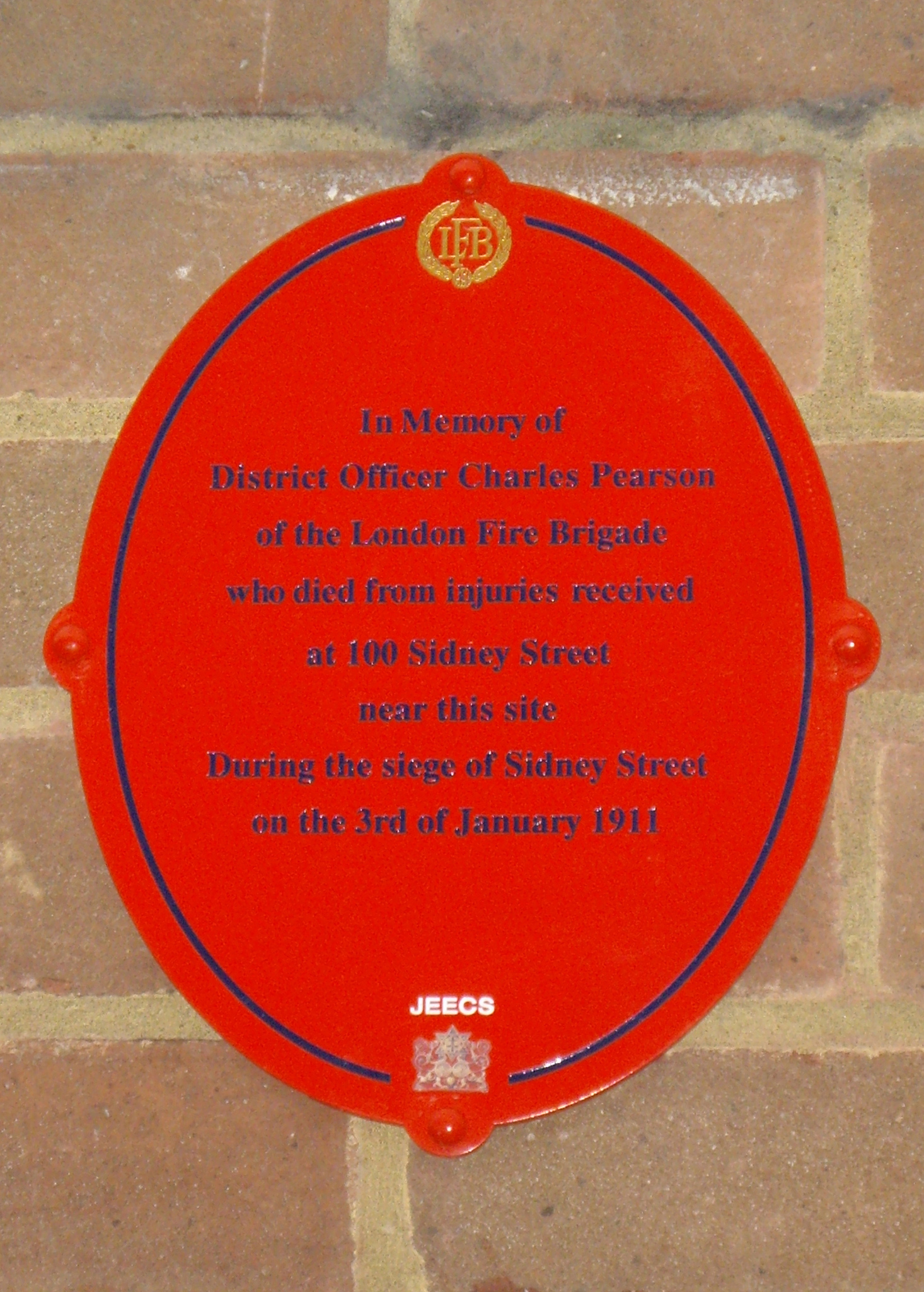 Siege of Sidney Street and Charles Pearson red and black plaque - In memory of District Officer Charles Pearson of the London Fire Brigade who died from injuries received at 100 Sidney Street near this site during the Siege of Sidney Street on 3rd January 1911