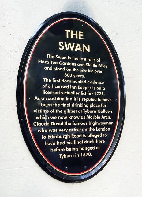 Claude Duval, Flora Tea Gardens and Skittle Alley, and The Swan, London black plaque - The Swan is the last relic of Flora Tea Gardens and Skittle Alley and stood on this site for over 300 years. The first documented evidence of a licensed Inn keeper is on a licensed victualler list for 1721. As a coaching Inn it is reputed to have been the final drinking place for victims of the gibbet of Tyburn Gallows which we now know as Marble Arch. Claude Duval the famous highwayman who was very active on the London to Edinburgh Road is alleged to have had his final drink here before being h