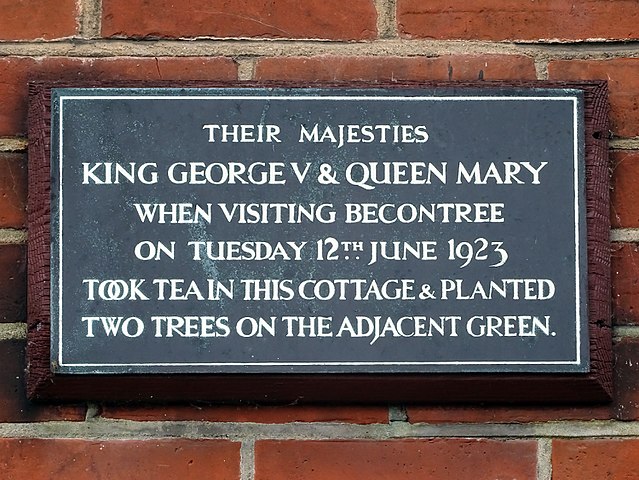 Mary of Teck and George V black plaque - Their majesties King George & Queen Mary when visiting Becontree on Tuesday 12th June 1923 took tea in this cottage & planted two trees on the adjacent green.