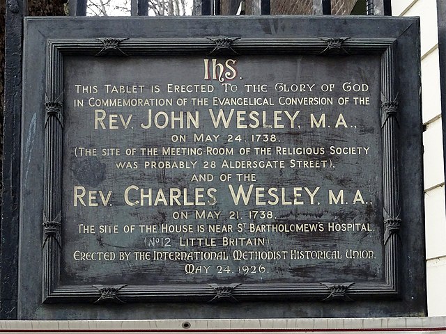 John Wesley and Charles Wesley black plaque - This tablet is erected to the glory of God in commemoration of the Evangelical Conversion of the Rev. John Wesley, M.A., on May 24, 1738. (This site of the meeting room of the Religious Society was probably 28 Aldersgate Street). And of the Rev. Charles Wesley, M.A., on May 21, 1738. The site of the house is near St Batholomew's Hospital. (No12 Little Britain). Erected by the International Methodist Historical Union. May 24 1926.